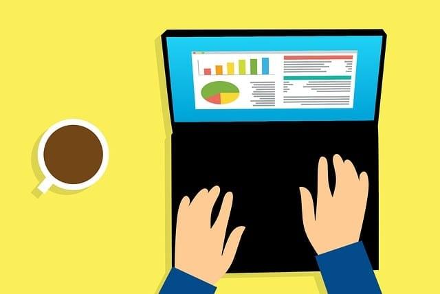 Illustration of hands typing on a laptop showing colorful charts and graphs on screen, with a cup of coffee nearby on a yellow background.