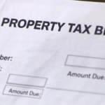 An image depicting the concept of property tax in South Carolina, illustrating various elements such as a calculator, a home, and documents related to property taxes, highlighting the importance of assessment ratios and the homestead exemption for primary residences in Charleston County. The scene emphasizes the process of estimating taxes by multiplying the property's assessed value by the total millage rate.