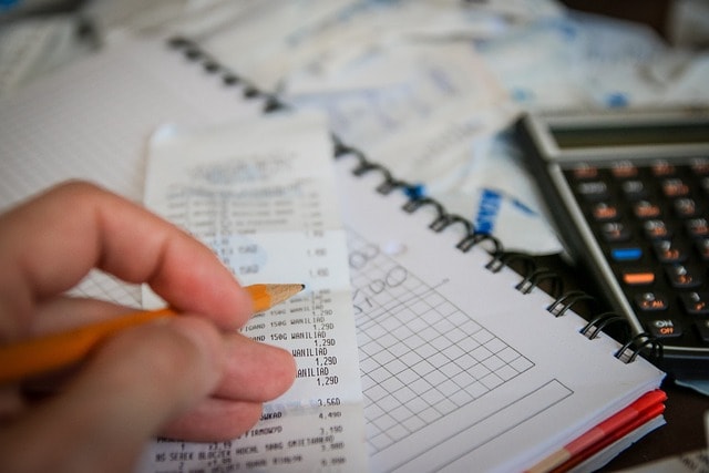 The hand of a person calculating property tax. Next to it there is a calculator.